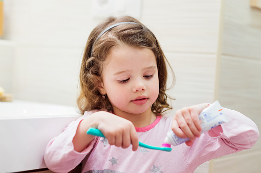 Child putting toothpaste on a toothbrush at Karl Hoffman Dentistry in Lacey, WA