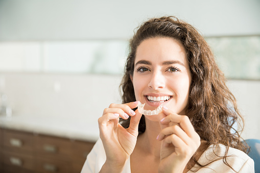Woman holding clear aligner in front of mouth at Karl Hoffman Dentistry in Lacey, WA Woman holding clear aligner in front of mouth at Karl Hoffman Dentistry in Lacey, WA