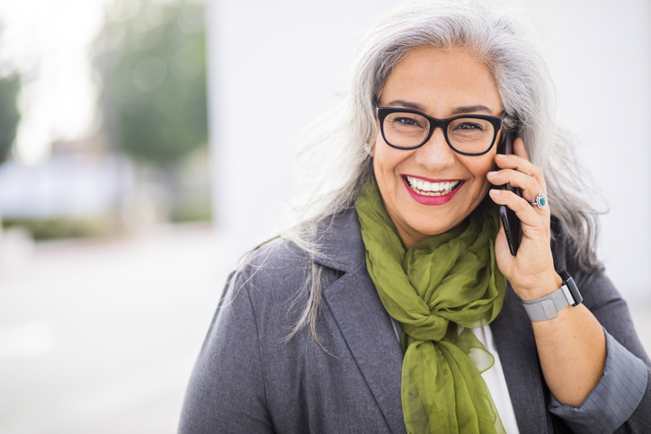 A smiling patient contacting Karl Hoffman Dentistry on a cell phone.