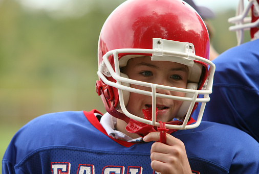 Kid wearing football gear and holding sports mouthguard at Karl Hoffman Dentistry in Lacey, WA