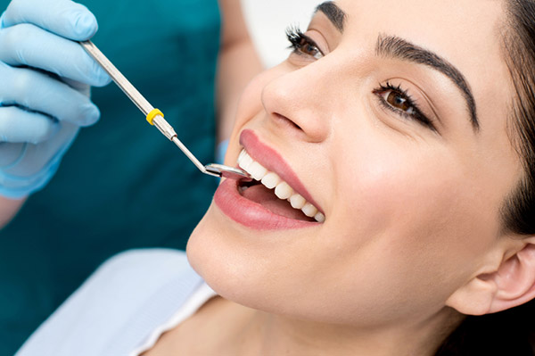 Smiling patient receiving exam with dental mirror at Karl Hoffman Dentistry in Lacey, WA